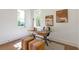 Bright office space featuring a unique wooden desk, modern artwork, and ample natural light from two large windows at 135 Cedarwood Ln, Roswell, GA 30075