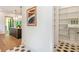 View from the hall of a pantry with custom built-in shelving, and black and gray hexagon tile flooring at 135 Cedarwood Ln, Roswell, GA 30075