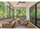 Relaxing covered porch with stylish seating, wood floors, and a view of the surrounding trees at 135 Cedarwood Ln, Roswell, GA 30075