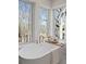 Soaking tub in bright bathroom offers view of natural surroundings from large windows at 135 Cedarwood Ln, Roswell, GA 30075