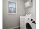 Bright laundry room featuring a modern washer and dryer, plus convenient shelving and a window at 1515 Bullard Pl, Powder Springs, GA 30127