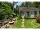 Quaint backyard area showcasing a stone pathway leading to a cottage with beautiful surrounding landscaping at 9032 Selborne Ln, Chattahoochee Hills, GA 30268