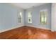 Light-filled bedroom featuring hardwood floors, blue walls, and three bright windows at 9032 Selborne Ln, Chattahoochee Hills, GA 30268