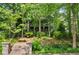 Landscaped front yard with stone steps leading to a charming home nestled among lush trees at 9032 Selborne Ln, Chattahoochee Hills, GA 30268