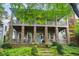 Two story home with stone porch supports, an open porch on the second story, and a manicured front yard at 9032 Selborne Ln, Chattahoochee Hills, GA 30268