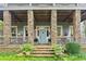 Stone porch with rocking chairs, ceiling fan and lush landscaping at 9032 Selborne Ln, Chattahoochee Hills, GA 30268