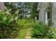 Lush garden pathway leading to an open field, surrounded by mature trees, plantings, and flowers at 9032 Selborne Ln, Chattahoochee Hills, GA 30268