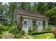 Charming guest house featuring a classic wooden door and surrounded by lush, vibrant landscaping at 9032 Selborne Ln, Chattahoochee Hills, GA 30268