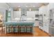 Bright, white kitchen boasts stainless steel appliances, center island with seating, and hardwood floors at 9032 Selborne Ln, Chattahoochee Hills, GA 30268