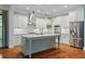 Stylish kitchen featuring white cabinets, a gray island, stainless steel appliances, and hardwood floors at 9032 Selborne Ln, Chattahoochee Hills, GA 30268