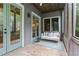 Charming screened porch with swing, stone floor, and view of the outdoor surroundings at 9032 Selborne Ln, Chattahoochee Hills, GA 30268