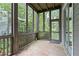 Relaxing screened-in porch with stone floors, wood beams, and a view of lush greenery at 9032 Selborne Ln, Chattahoochee Hills, GA 30268