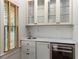 A well-appointed wet bar with glass-front cabinets, marble countertop, and a wine fridge at 9032 Selborne Ln, Chattahoochee Hills, GA 30268