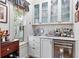 Elegant wet bar with glass-front cabinets and marble countertop at 9032 Selborne Ln, Chattahoochee Hills, GA 30268