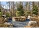 Relaxing stone fire pit with seating and grill in wooded setting at 207 Mitchell Ln, Woodstock, GA 30188