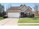 Tan house with white garage door, landscaping, and a brick accent at 4410 Chaney Ct, Cumming, GA 30028