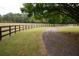 Scenic driveway winds through verdant fields bordered by classic wooden fences and mature trees at 75 Rivercreek Xing, Kingston, GA 30145
