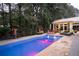 Beautiful backyard pool with outdoor furniture, black metal fence and lush landscaping at night at 75 Rivercreek Xing, Kingston, GA 30145