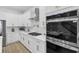 White kitchen with gas cooktop, stainless steel double oven, and gold hardware at 2438 2Nd Nw St, Atlanta, GA 30318