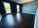 Spacious bedroom with dark laminate flooring and teal walls, featuring two large windows at 1760 Marceau Dr, Conley, GA 30288