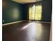 Bedroom with dark laminate flooring, teal walls, and a window with sheer curtains at 1760 Marceau Dr, Conley, GA 30288