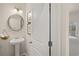 Elegant powder room with a pedestal sink, round mirror, and stylish wall art at 2210 Cormac St, East Point, GA 30344