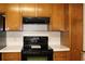 Black electric range and oven with wood cabinets above and below at 410 Raven Dr, Canton, GA 30115