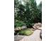 Landscaped backyard features stone accents, lush greenery, and a charming walkway to pool at 923 Little Darby Ln, Suwanee, GA 30024