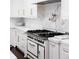 Gas range with white cabinets and marble backsplash at 923 Little Darby Ln, Suwanee, GA 30024