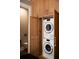 Convenient laundry room with stacked washer and dryer units and oak cabinets at 923 Little Darby Ln, Suwanee, GA 30024