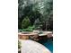 Scenic outdoor pool area featuring lush greenery, spa and a cozy fire pit at 923 Little Darby Ln, Suwanee, GA 30024