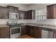 Kitchen featuring stainless steel appliances, granite countertops, and dark wood cabinetry at 7369 Saint Peter Way, Fairburn, GA 30213
