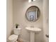 Small, updated powder room with pedestal sink and a round mirror at 591 River Gardens Se Dr, Atlanta, GA 30354