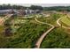 Aerial view showcasing a winding boardwalk through lush greenery, a putt-putt course, and a pond at 120 Stonehouse Dr, Cumming, GA 30040