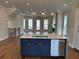 Kitchen island with stainless steel dishwasher, hardwood floors, and view of living room with fireplace at 120 Stonehouse Dr, Cumming, GA 30040