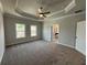 Large carpeted bedroom with tray ceiling, ceiling fan, and two windows at 120 Stonehouse Dr, Cumming, GA 30040