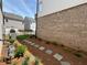 Landscaped side yard with stone pavers, mulch, and green plants against a brick wall at 120 Stonehouse Dr, Cumming, GA 30040