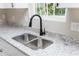 Bright kitchen featuring stainless steel double sink, granite countertop, and black faucet fixture at 121 Hunters Ln, Powder Springs, GA 30127