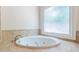 Oval jacuzzi bathtub with tile surround, and large window in corner at 630 Darlington Commons Ne Ct, Atlanta, GA 30305