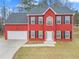 Two-story red brick house with a white door, black shutters, and a two-car garage at 1029 Chaterly Ct, Riverdale, GA 30296