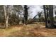 Large backyard with scattered leaves beneath a canopy of bare trees, with a wooden fence in the distance at 345 Lexington Dr, Lawrenceville, GA 30046