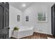 Modern bathroom featuring corner tub, wood-look floors, and dark door at 3569 Lynne Rd, Powder Springs, GA 30127