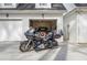 View of a motorcycle parked in front of a garage with an open bay and classic car inside at 10 Moss Landing Se Rd, Acworth, GA 30102