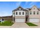 Two-story townhome with white and brick exterior, two-car garage, and landscaping at 8194 Tiger Way, Riverdale, GA 30274