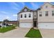 Two-story townhome with white and brick exterior, two-car garage, and landscaping at 8218 Tiger Way, Riverdale, GA 30296