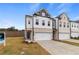 Two story townhome with white and brick exterior, two car garage, and landscaping at 8218 Tiger Way, Riverdale, GA 30296