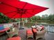 Relaxing deck overlooking a lake, furnished with wicker seating and a red umbrella at 897 Winding Trl, Lawrenceville, GA 30046