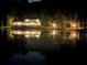 Stunning lakefront home at night, beautifully lit and reflecting in the water at 897 Winding Trl, Lawrenceville, GA 30046