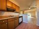 Kitchen with wooden cabinets, built in dishwasher and view to living room at 8263 Canyon Forge Dr, Riverdale, GA 30274