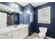 Modern bathroom with a white vanity, large mirror, window, and toilet with blue accent wall at 183 Applewood Ln, Acworth, GA 30101